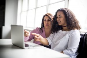 A Mother And Teenage Daughter Looking At Laptop Together